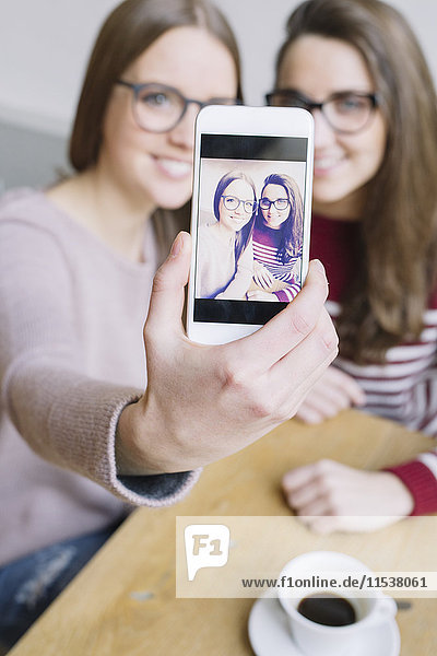 Two young women taking a selfie with smartphone