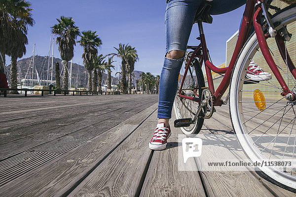 Leg of young woman sitting on bicycle