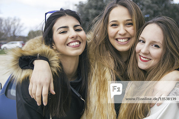Gruppenbild von drei glücklichen jungen Frauen Arm in Arm