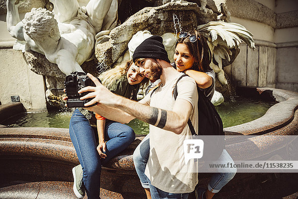 Österreich  Wien  Gruppe von drei Freunden  die einen Selfie vor dem Brunnen in der Hofburg nehmen.