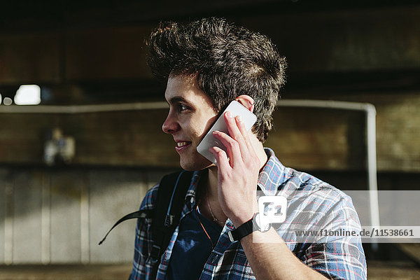 Smiling young man telephoning with smartphone