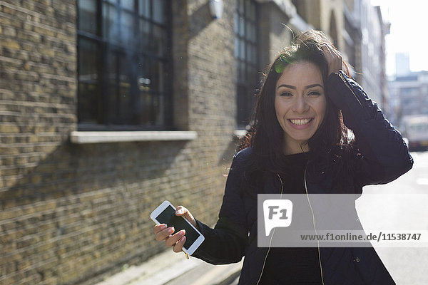 Porträt einer glücklichen jungen Frau mit Handy auf der Stadtstraße