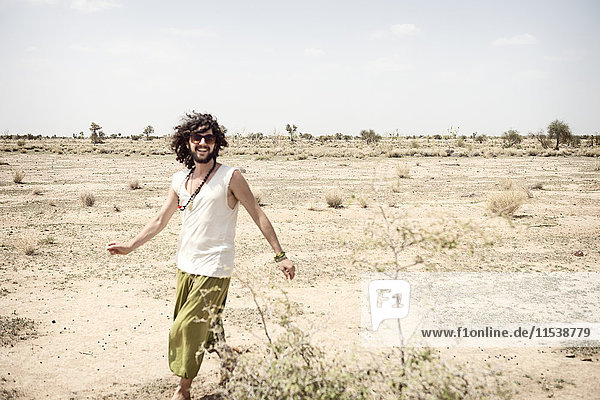 Lächelnder Mann mit Sonnenbrille  der allein in der Wüste unterwegs ist.