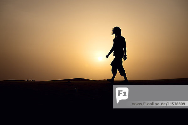 Silhouette of man walking on dune