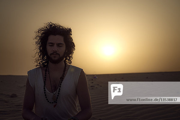 Man meditating in the desert with eyes closed