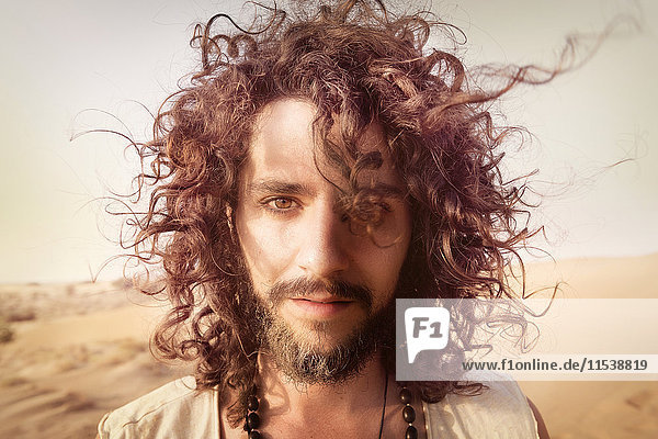 Porträt eines Mannes mit Bart und lockigem Haar in der Wüste