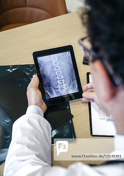 Arzt betrachtet Röntgenbild auf digitalem Tablett