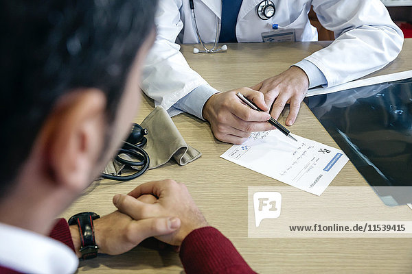 Doctor writing prescription for patient