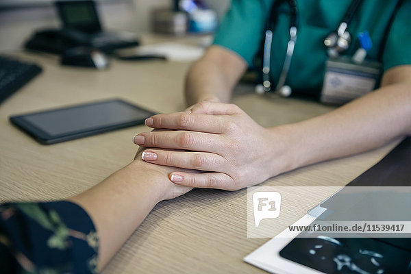 Doctor holding patient's hand on table