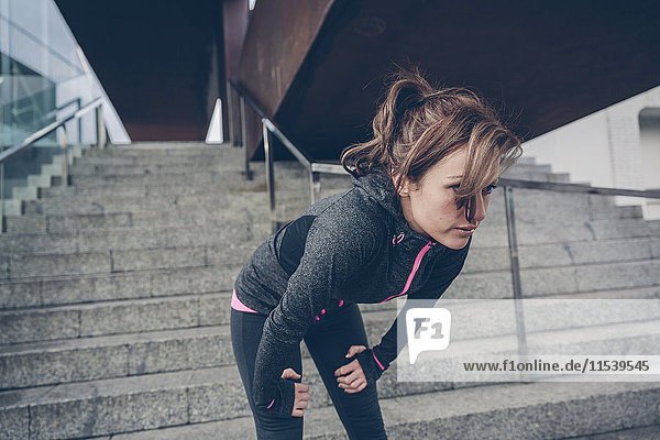 Tired woman resting in front of stairs after running
