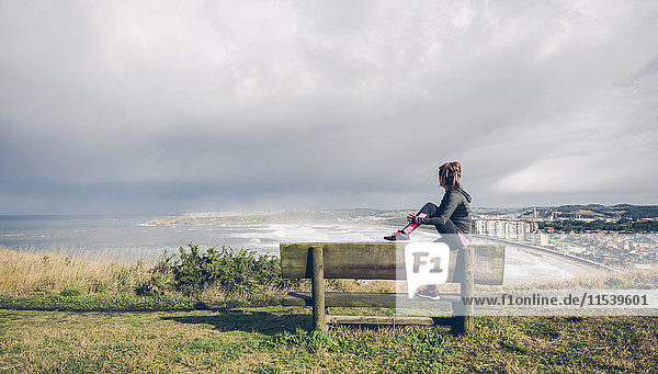 Sportliche mittlere erwachsene Frau auf Klippe mit Blick aufs Meer