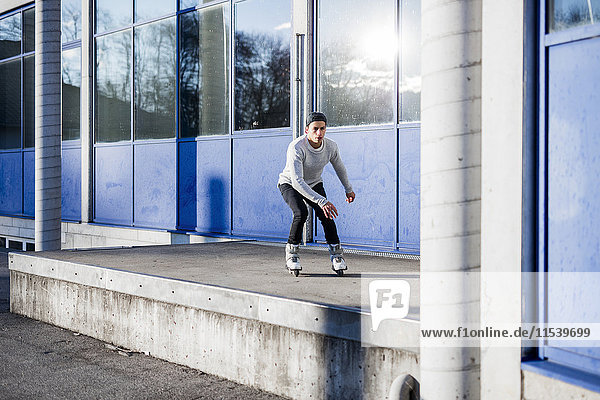 Junger Mann beim Inline-Skaten entlang eines Gebäudes