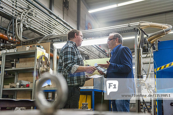 Zwei Männer mit digitalem Tablett im Fabrikgespräch