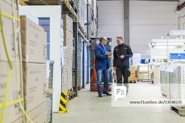 Manager and warehouseman dicussing logistics in storage
