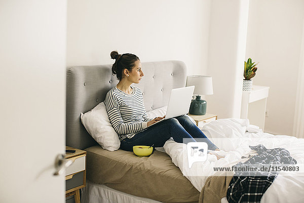 Woman sitting in bed using laptop