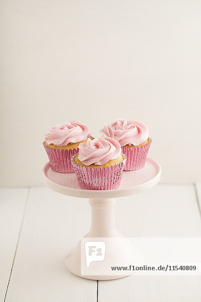 Drei rosa Tassenkuchen auf einem Kuchenständer