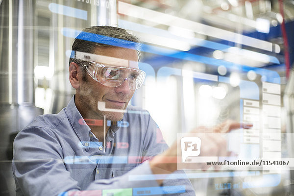 Man wearing safety goggles using transparent touchscreen device