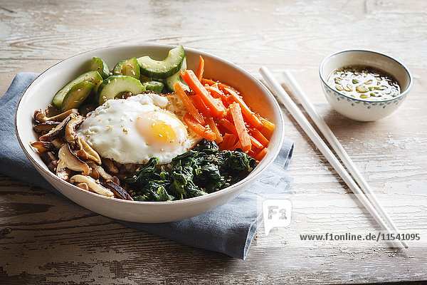 Vegetarische koreanische Reisschüssel mit Champignon  Spinat  Gurke  Karotte und Spiegelei