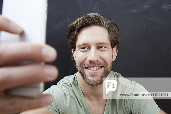 Porträt eines lächelnden jungen Mannes mit einem Selfie mit Smartphone