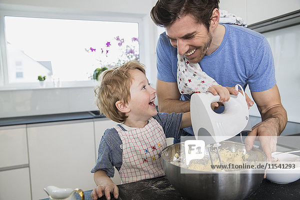 Father and son preparing waffle dough in kitchen