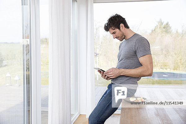 Mann zu Hause mit digitalem Tablett