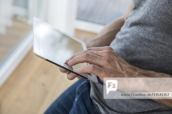 Mann zu Hause mit digitalem Tablett