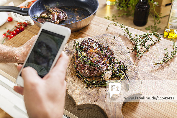 Man taking celll phone picture of prepared steaks