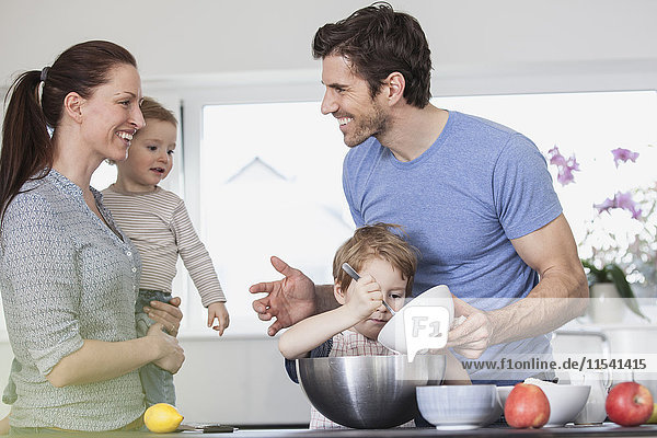Familie mit zwei Kindern beim Kochen in der Küche