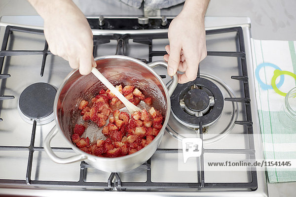 Man stirring strawberries on gas stove