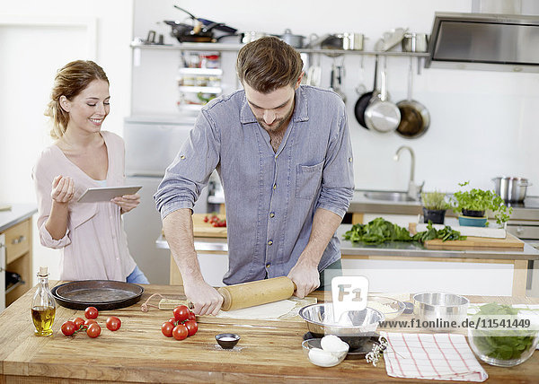 Couple preparing pizza dough in kitchen