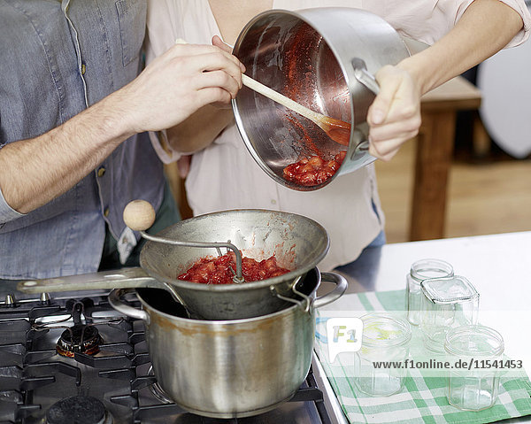 Paar Zubereitung von heißen Erdbeeren auf dem Gasherd
