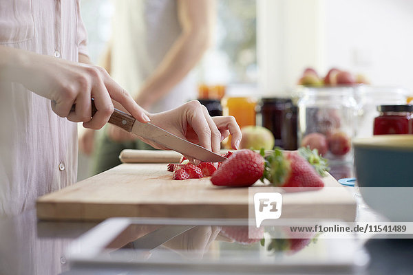 Frau schneidet Erdbeeren in der Küche