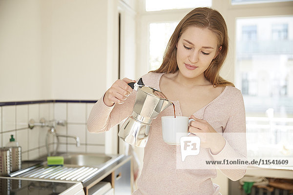 Junge Frau  die Kaffee in eine Tasse gießt