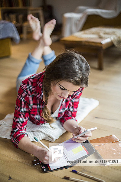 Young woman at home working with smartphone