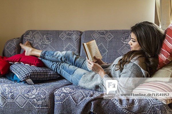 Junge Frau zu Hause beim Lesen eines Buches