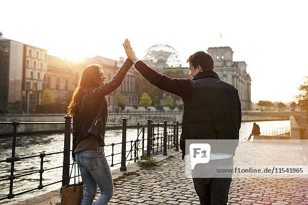 Germany  Berlin  young walking along River Spree high fiving