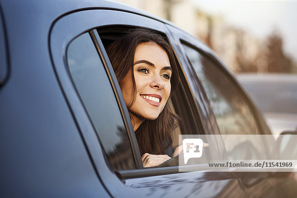 Smiling young woman looking out of car window