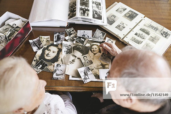 Seniorenpaar mit Fotoalben und alten Fotografien zu Hause