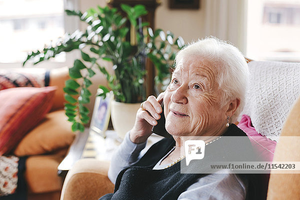 Portrait of smiling senior woman telephoning with smartphone at home