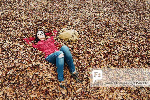 Frau entspannt sich auf mit Herbstlaub bedecktem Waldboden