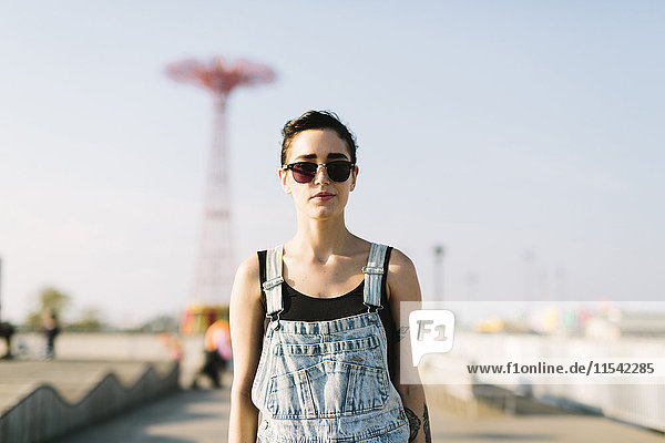 USA  New York  Coney Island  junge Frau mit Jahrmarktsfahrt im Hintergrund