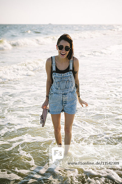 USA  New York  Coney Island  Portrait einer glücklichen jungen Frau  die im Meer watet.