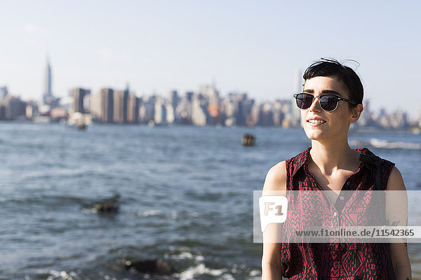USA  New York City  Portrait einer lächelnden jungen Frau mit Sonnenbrille