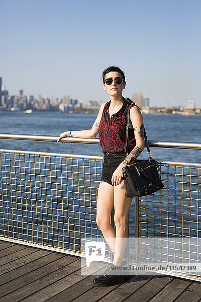 USA  New York City  Williamsburg  tätowierte junge Frau auf Geländer gestützt