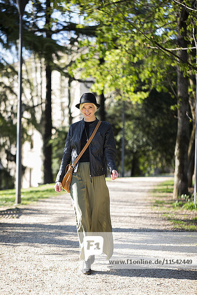 Italien  Verona  Porträt einer modischen blonden Frau  die im Frühling in einem Park spazieren geht.