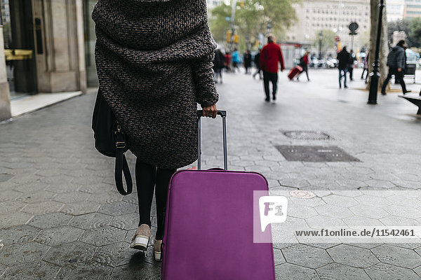 Spain  Barcelona  young woman with suitcase walking in the city