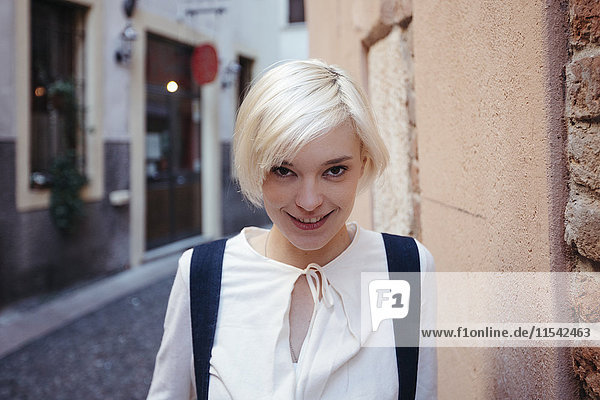 Italien  Verona  Porträt einer lächelnden blonden Frau  die in einer engen Gasse steht