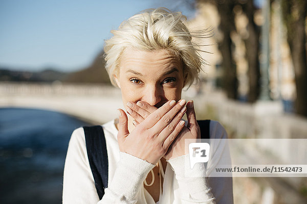 Italien  Verona  Porträt einer blonden Frau  die den Mund mit den Händen bedeckt.