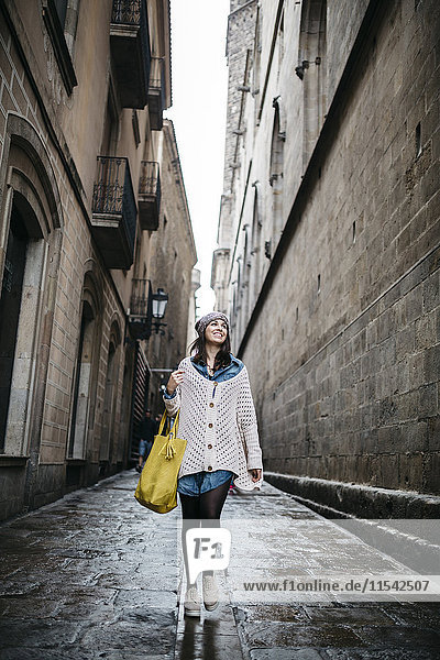 Spain  Barcelona  young woman walking in an alley