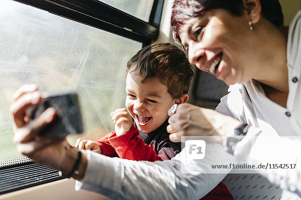 Happy little boy on his first train ride having fun with his mother